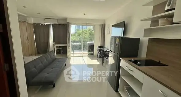 Modern open-plan living room with sleek kitchen and balcony view.
