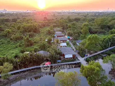 Scenic aerial view of rural homes surrounded by lush greenery at sunset, offering serene living environment.