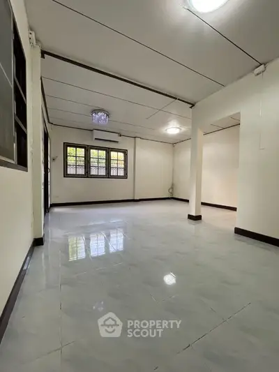 Spacious open-plan living area with tiled flooring and large windows for natural light.