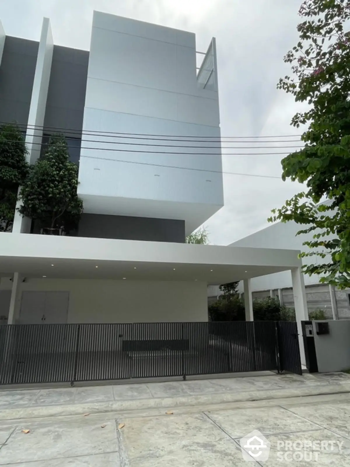 Modern minimalist building exterior with sleek design and lush greenery.