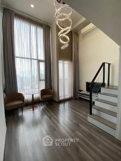 Modern living room with high ceilings and elegant staircase in a stylish apartment.