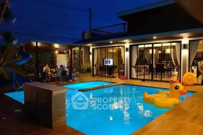 Luxurious modern home with illuminated pool and stylish outdoor seating at night.