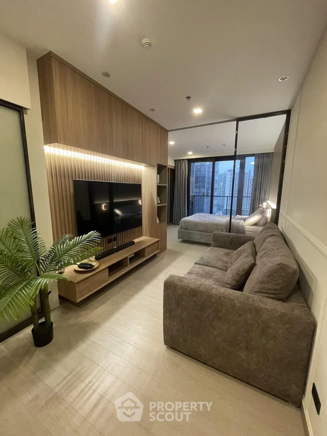Modern living room with stylish decor and city view, featuring a cozy sofa and sleek entertainment unit.