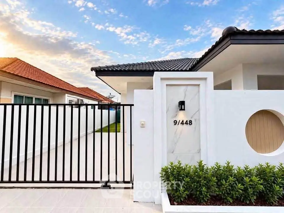Modern single-story house with sleek design and gated entrance in a serene neighborhood.