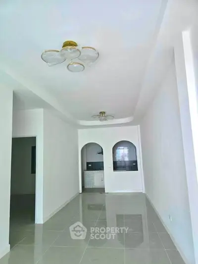 Spacious modern living room with sleek tile flooring and elegant ceiling lights.