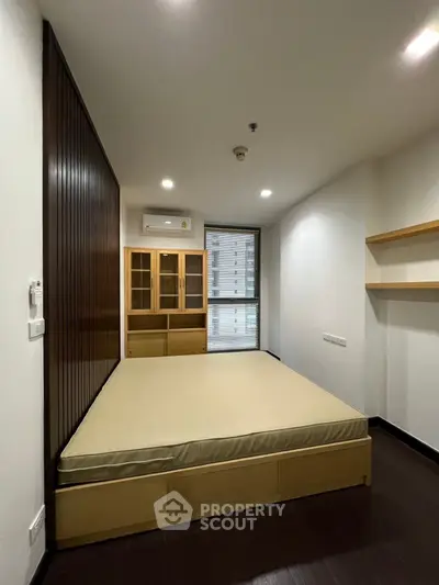 Modern bedroom with built-in storage and large window view in urban apartment