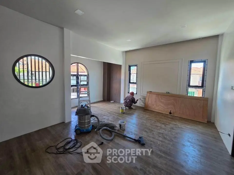 Spacious living room with wooden flooring and unique circular window design