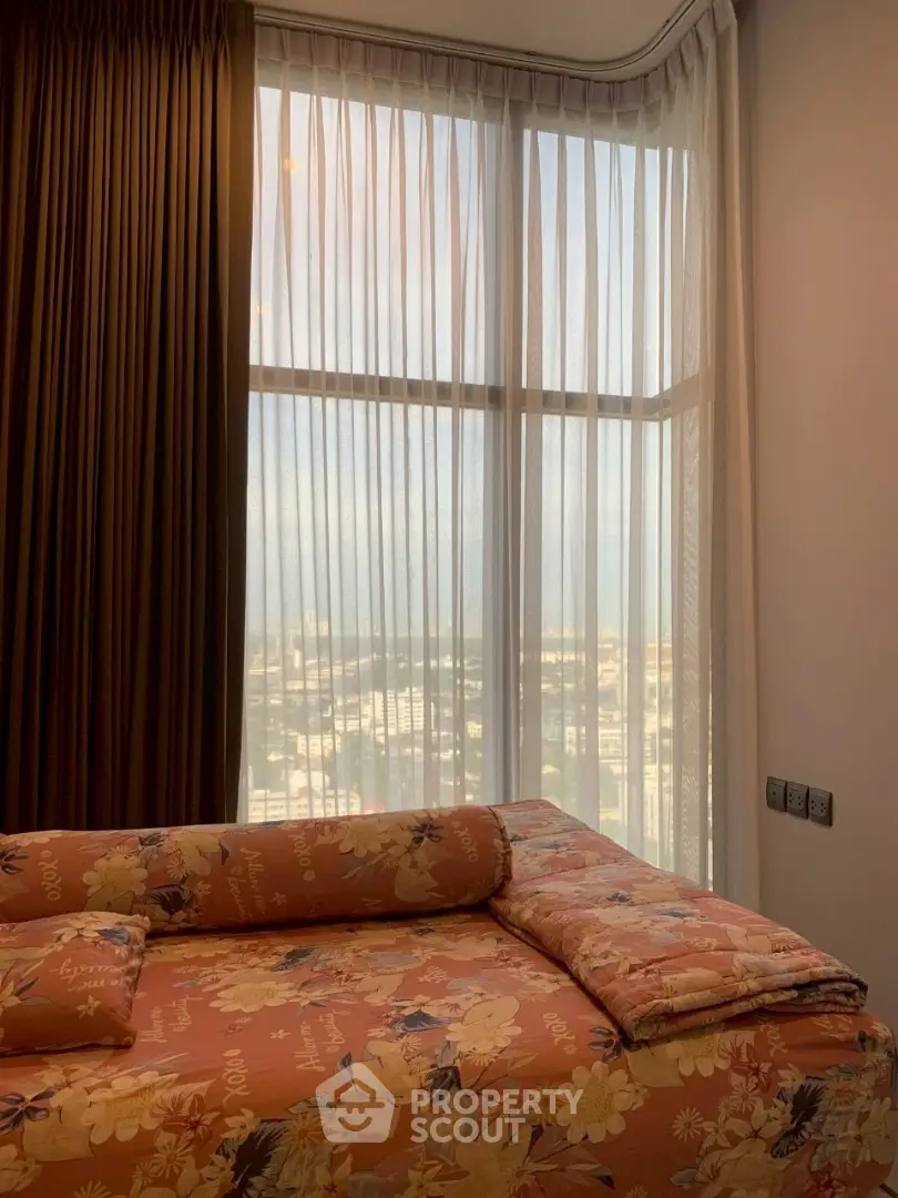 Cozy bedroom with floral bedding and large window offering a city view.