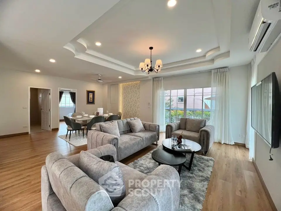 Spacious living room with elegant gray sofas, wooden flooring, and modern chandelier, perfect for family gatherings.