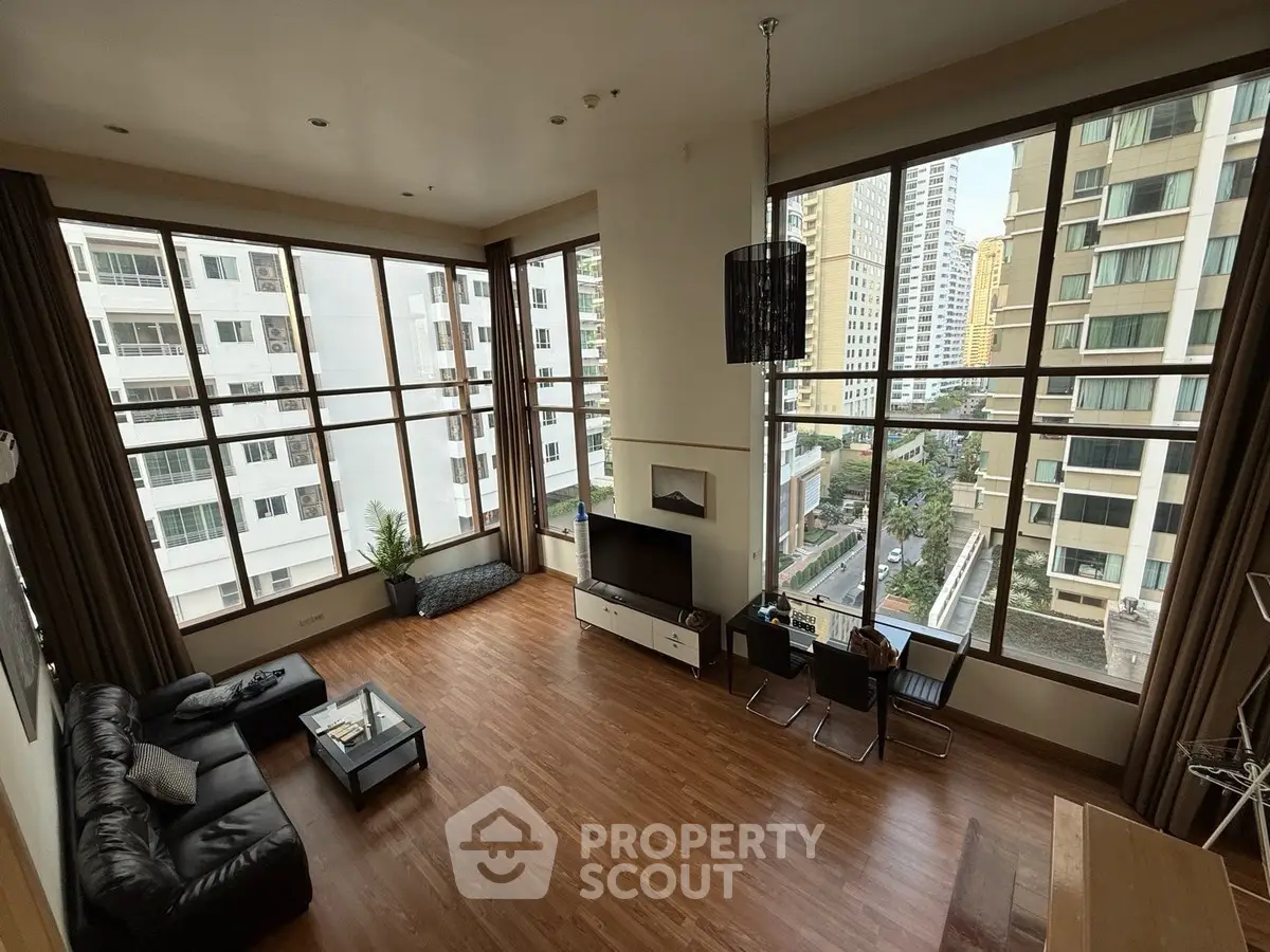 Spacious modern living room with large windows and city view, featuring elegant decor and hardwood floors.