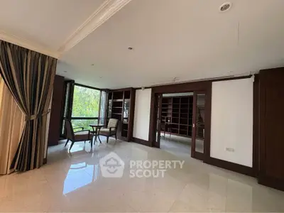 Spacious living room with elegant wooden accents and large windows offering a serene garden view.