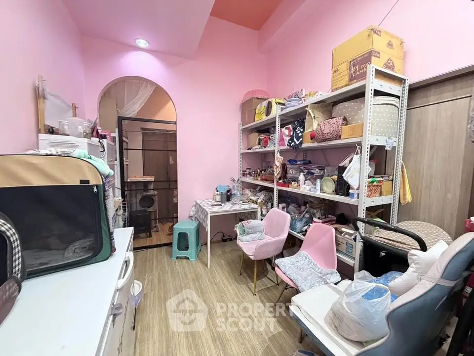 Charming storage room with pink walls and organized shelving in a cozy home.