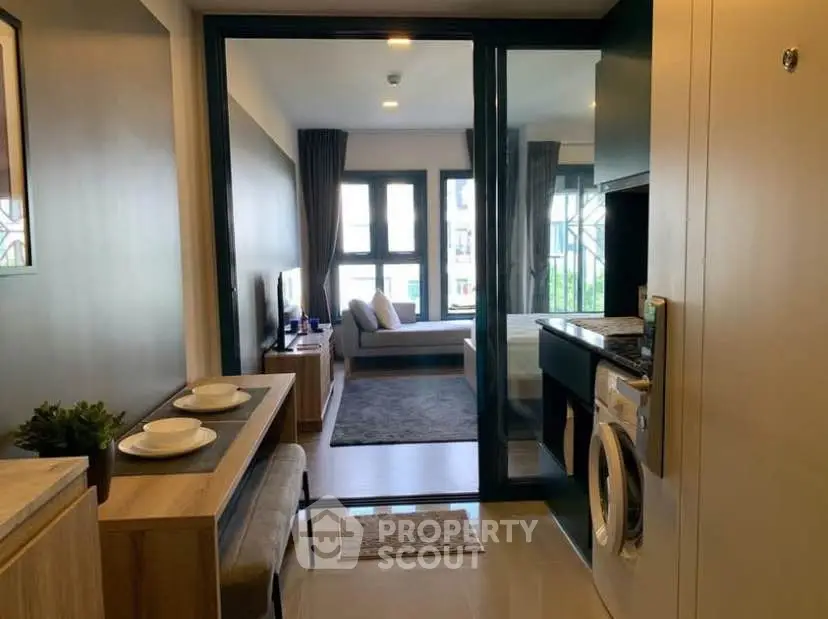 Modern apartment interior with open layout, featuring a cozy living area and in-unit washing machine.