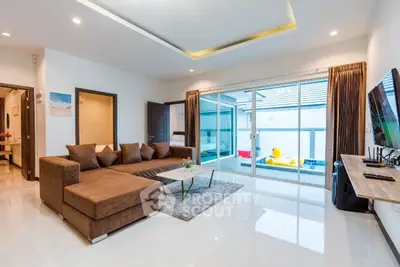 Modern living room with pool view, featuring a stylish brown sectional sofa and sleek decor.