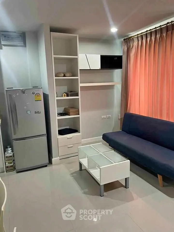 Modern living room with sleek furniture and natural light, featuring a compact fridge and stylish shelving.