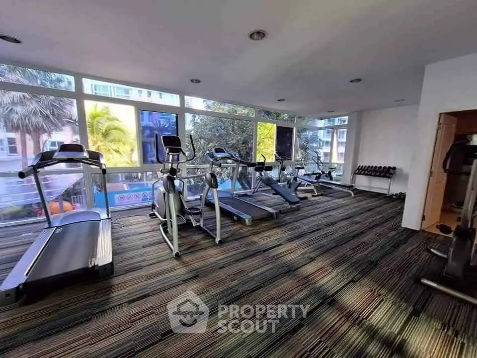 Spacious gym with modern equipment and large windows offering a scenic view.