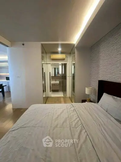 Modern bedroom with mirrored closet doors and elegant lighting