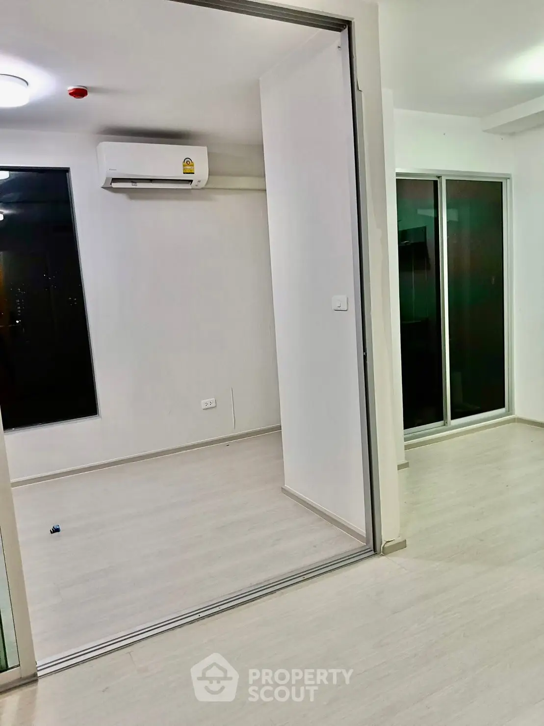 Modern interior with sliding glass doors and air conditioning unit in a bright, minimalist room.
