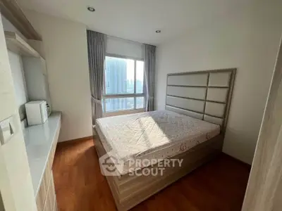 Bright bedroom with large window and modern furnishings, featuring a comfortable bed and wooden flooring.