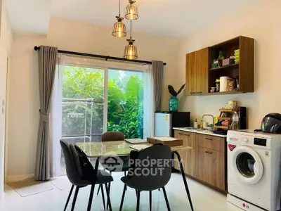 Modern kitchen with dining area, washing machine, and garden view