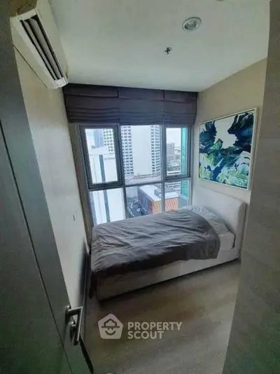 Cozy bedroom with city view, featuring modern decor and natural light.