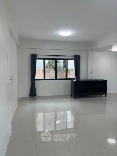 Spacious empty living room with glossy tiled floors and large window.