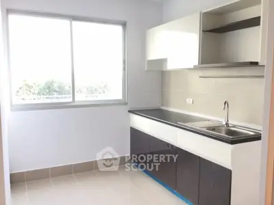 Modern kitchen with sleek cabinetry and large window for natural light.
