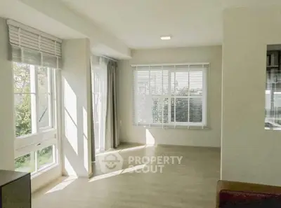 Spacious sunlit living room with large windows and modern blinds in a contemporary home.