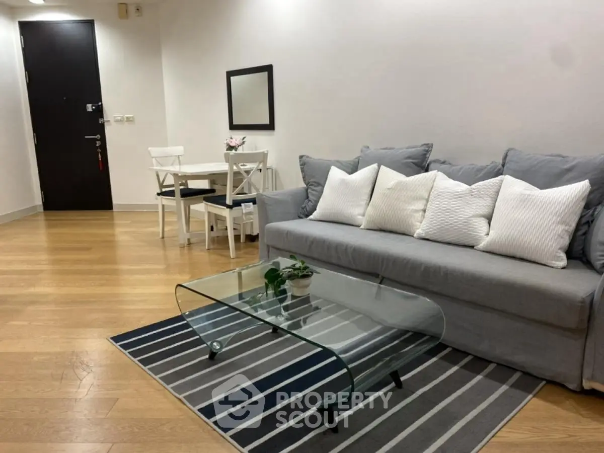 Modern living room with stylish gray sofa, glass coffee table, and dining area, perfect for urban living.