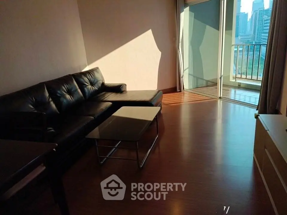 Spacious living room with modern leather sofa and city view balcony.