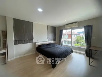 Spacious bedroom with large window and modern furnishings in a bright, airy home.