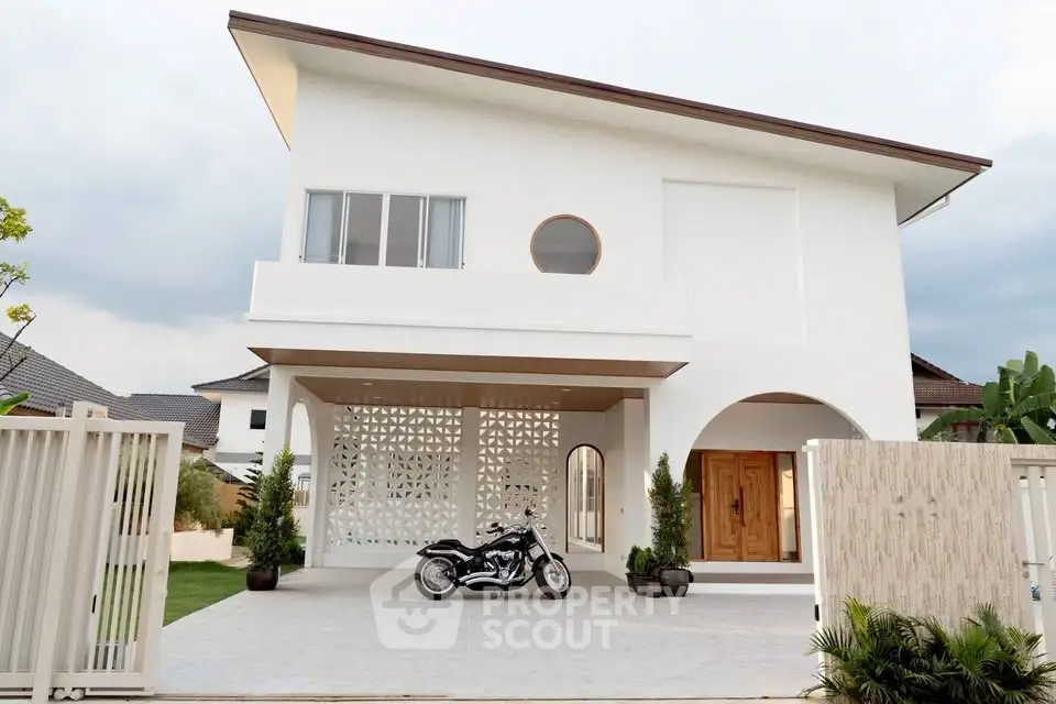Modern white two-story house with unique geometric design and motorcycle parked in front.