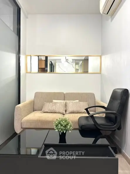 Modern living room with beige sofa, black armchair, and sleek glass coffee table in a cozy setting.