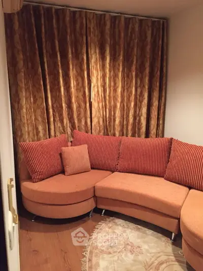 Cozy living room with stylish round orange sofa and elegant curtains, perfect for relaxation.