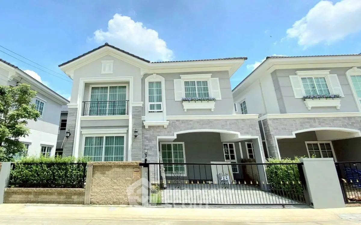 Charming two-story house with modern facade and gated driveway under clear blue sky.