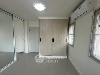 Modern bedroom with sleek wardrobe and air conditioning unit, perfect for comfortable living.