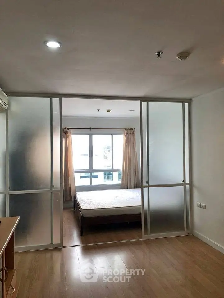 Modern bedroom with frosted glass sliding doors and large window for natural light.