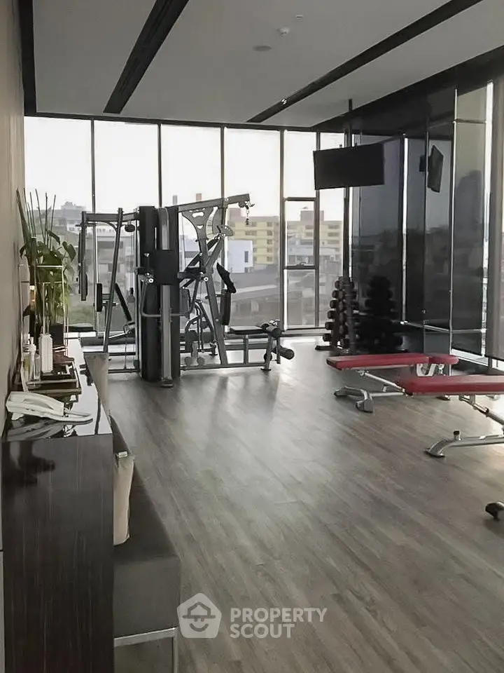 Modern gym with large windows and fitness equipment in a high-rise building.