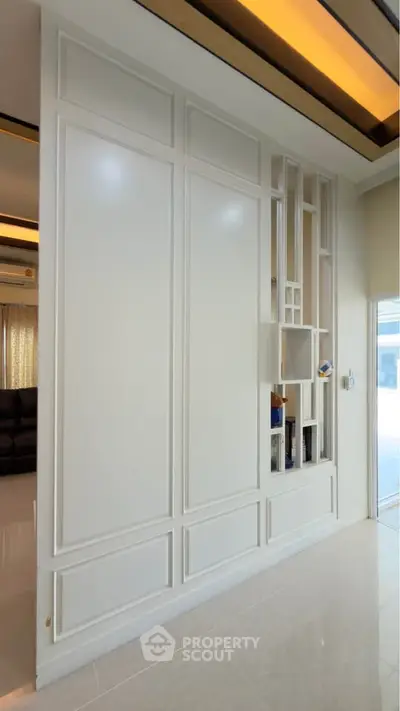 Modern interior with sleek white wall paneling and open shelving in a stylish living space.