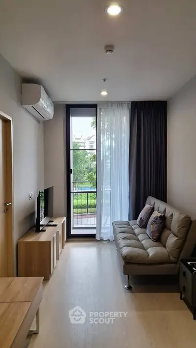 Modern living room with sleek furniture and large window offering a serene garden view.
