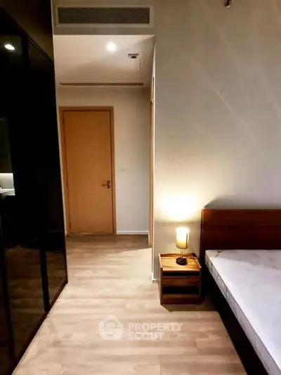 Modern bedroom with wooden flooring and sleek furniture in a stylish apartment.