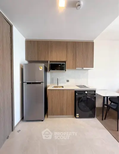 Modern kitchen with sleek appliances and wooden cabinetry in a stylish apartment.