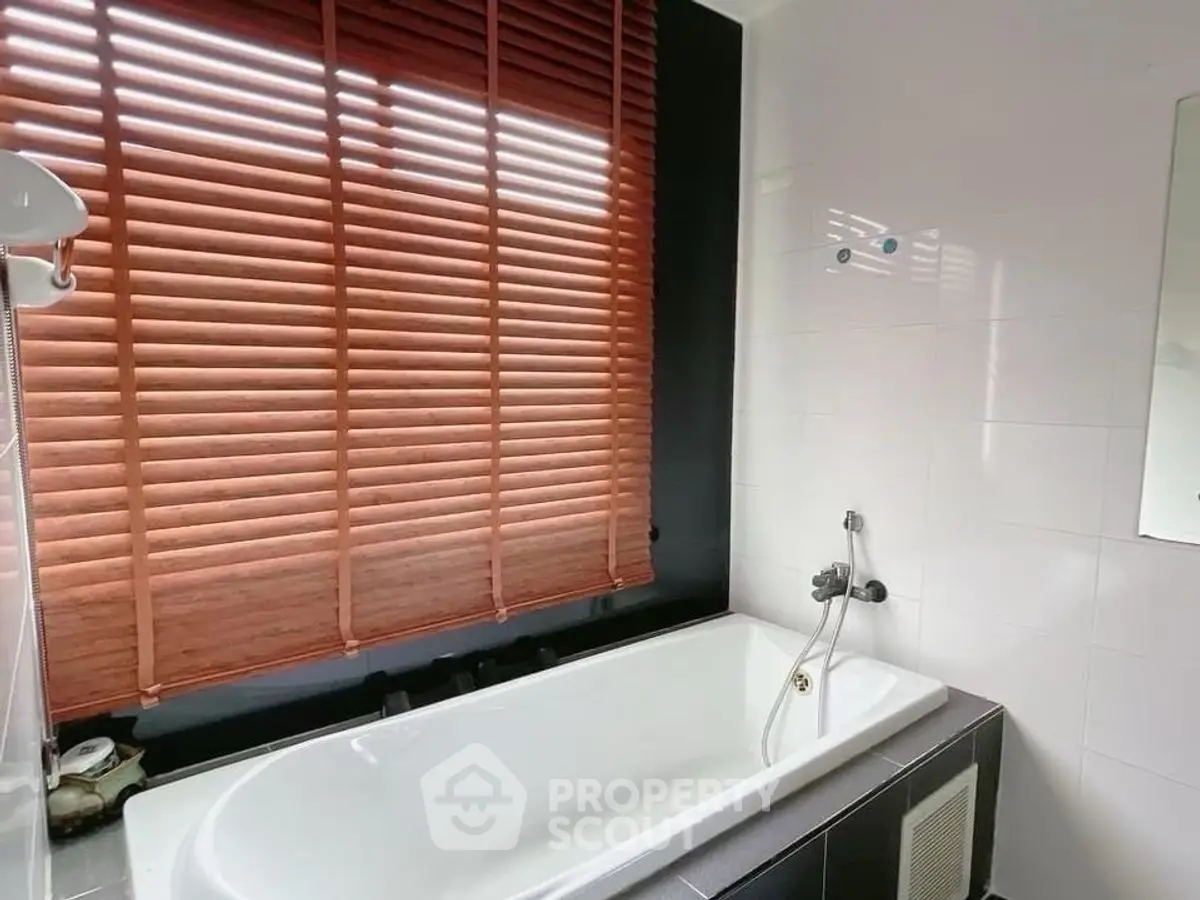Modern bathroom with sleek bathtub and wooden blinds