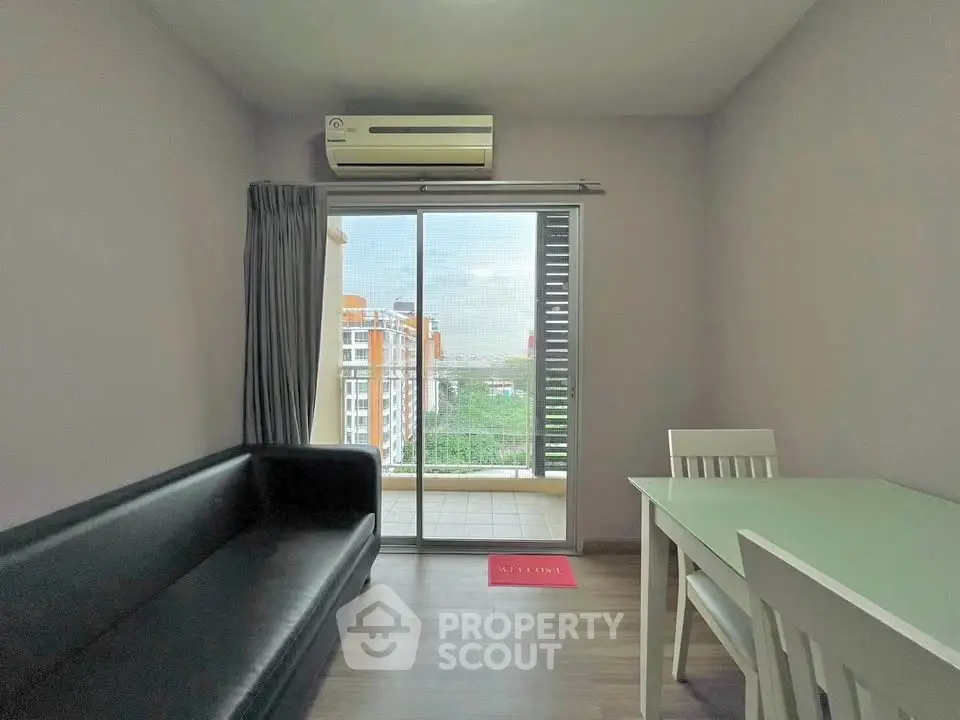 Modern living room with balcony view, featuring sleek furniture and air conditioning.