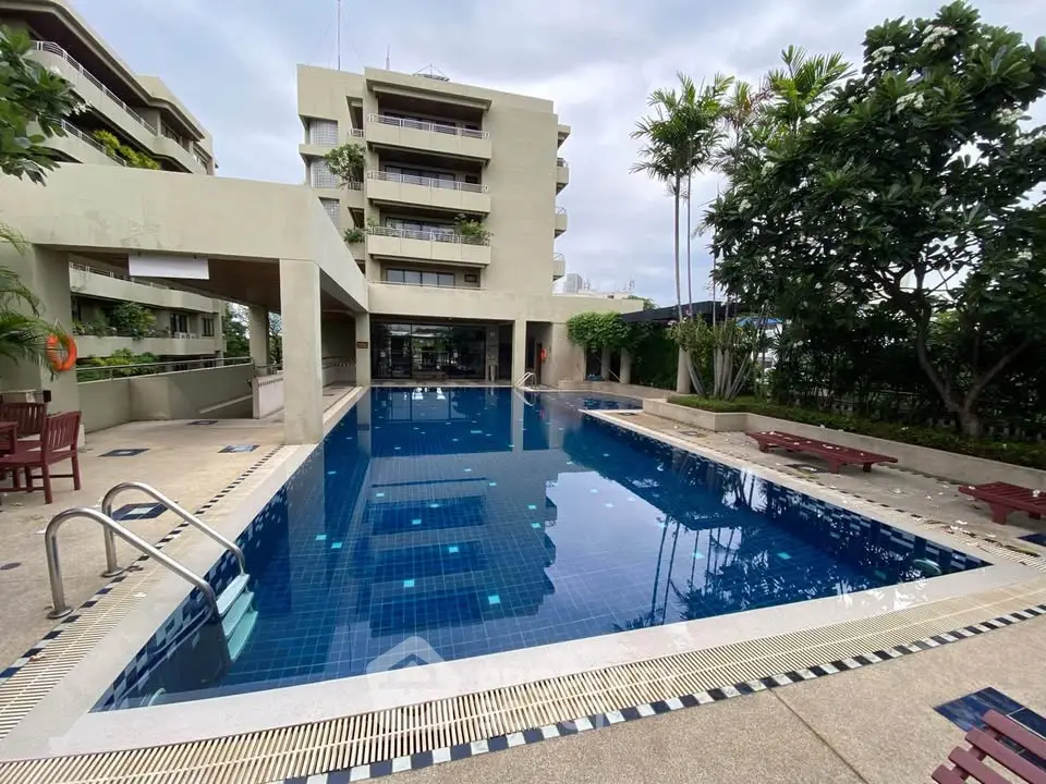 Luxurious residential building with a pristine outdoor swimming pool and lush greenery.