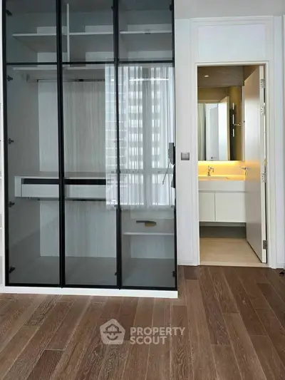 Modern interior with glass closet and sleek bathroom design, featuring elegant wood flooring.