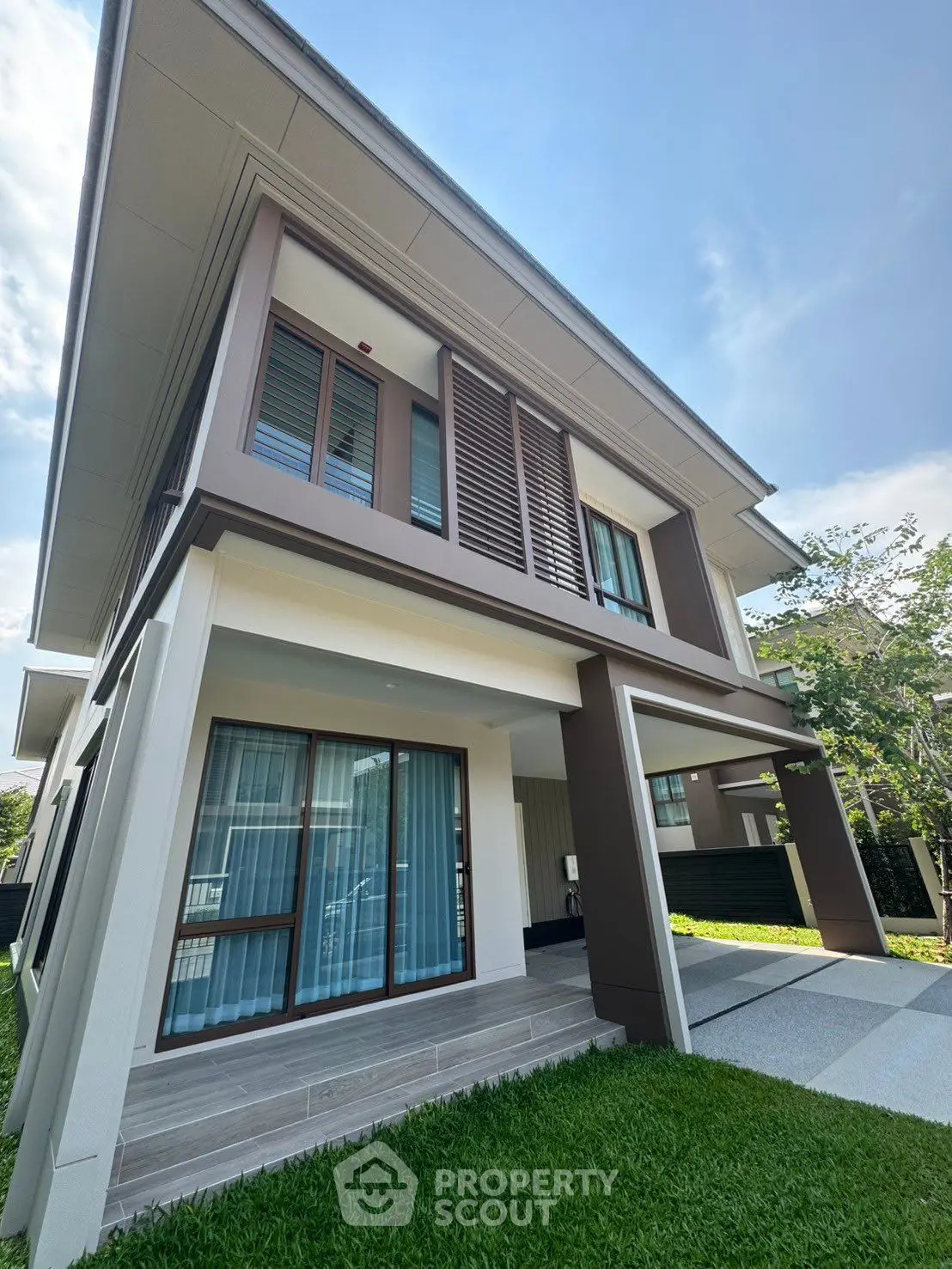 Modern two-story house with large windows and lush green lawn