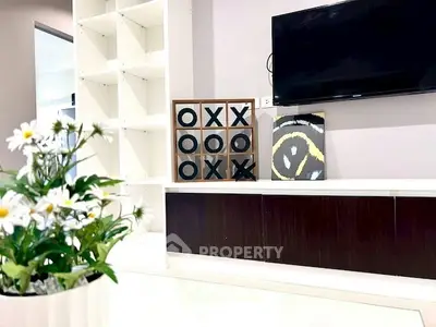 Modern living room with stylish decor and wall-mounted TV, featuring a unique tic-tac-toe art piece.