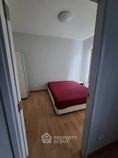 Cozy bedroom with wooden flooring and minimalist design, featuring a comfortable bed and ample natural light.