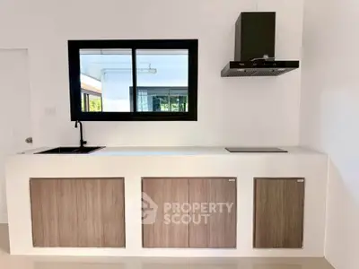 Modern minimalist kitchen with sleek cabinetry and black range hood